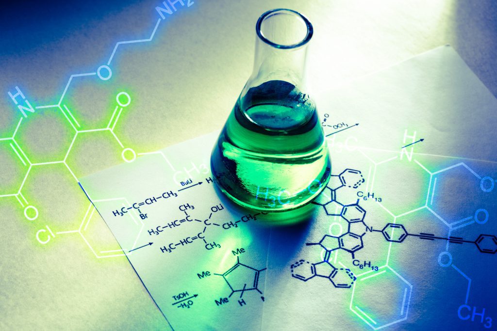 A flasks with green liquid sits on a table covered with chemical structure diagrams and molecular formulas in vivid blue and green hues.
